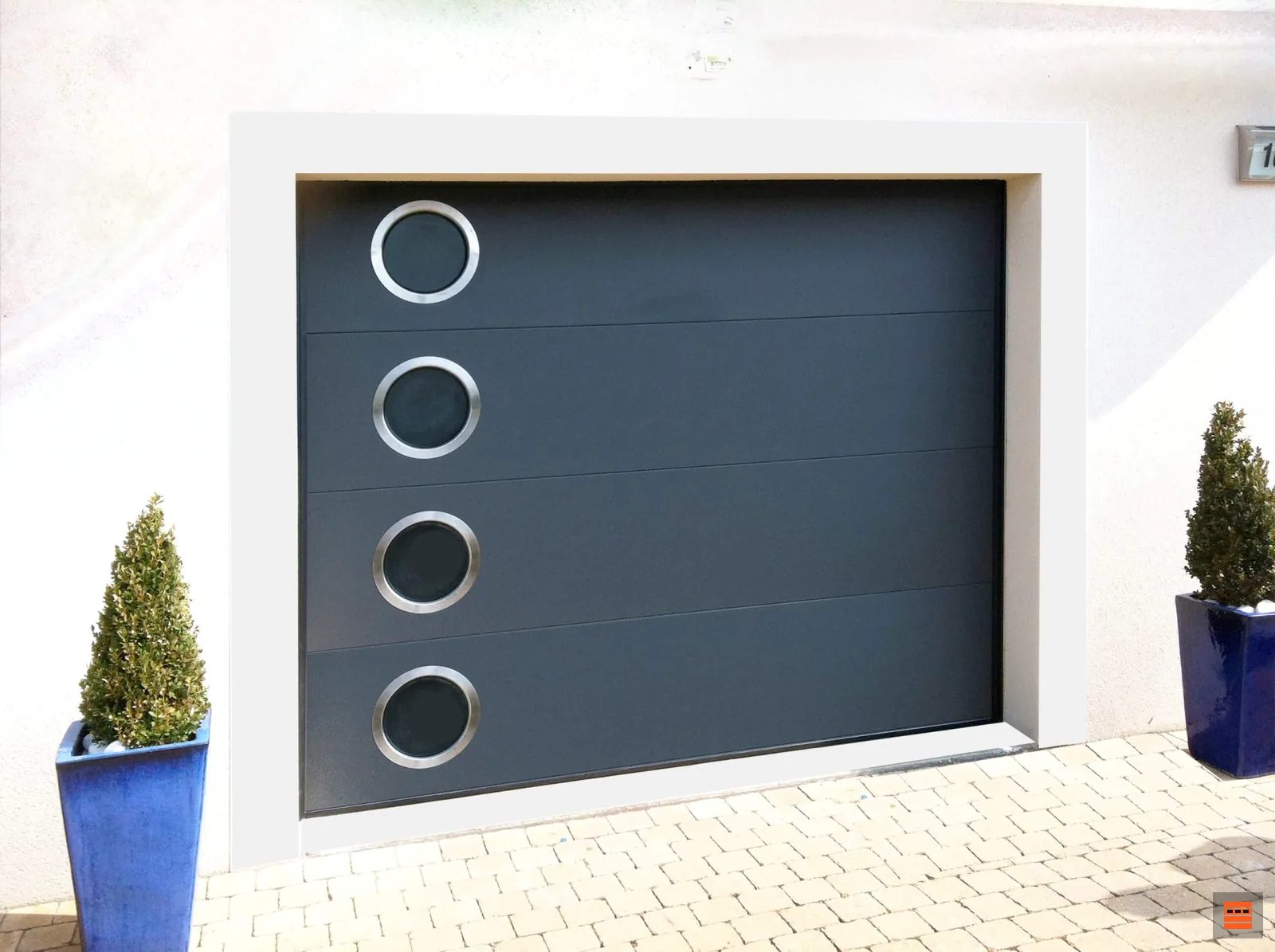 Porte de garage sectionnelle grise à hublots ronds sur une maison